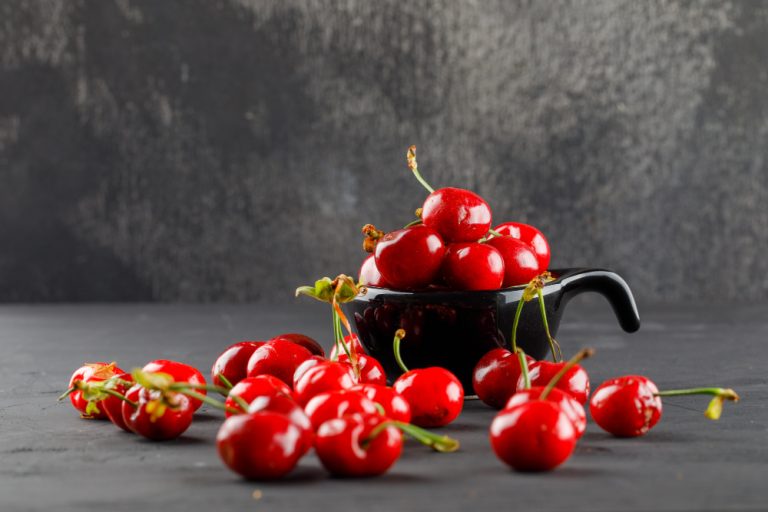 tasty-cherries-black-scoop-grungy-grey-table-side-view